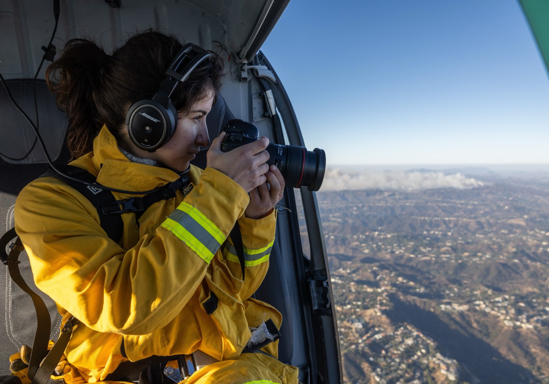 A photojournalist in a helicopter photographing the landscape below